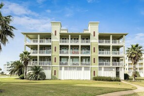 Un hotel de diversos pisos amb balcons, teulada plana i un jardí ben cuidat.
