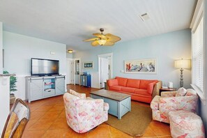 Ein Wohnzimmer mit Fernseher, Deckenventilator, Sofa und Couchtisch.