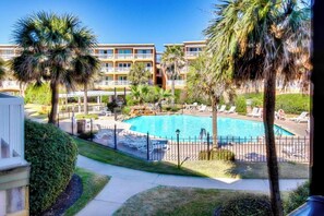Ein Hotel mit Swimmingpool, umgeben von Palmen und Liegestühlen.