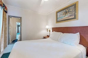 Ein Hotelzimmer mit einem großen Bett, einem Nachttisch, einer Wandleuchte, einem Spiegel und einem Gemälde.