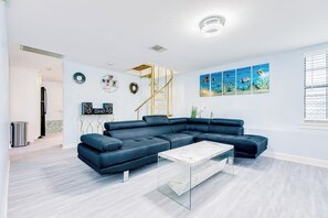 Ein modernes Wohnzimmer mit einem Ecksofa, einem Glastisch und einer Wendeltreppe.