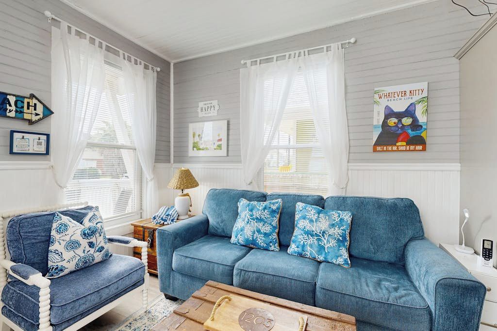 A living room with a blue sofa, a white armchair, and a wooden coffee table.