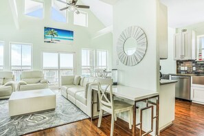 A spacious living area with a dining table, white sofas, and a large mirror. - 8-Mile Beachfront - Gulf Views & Dog-Friendly (Galveston)