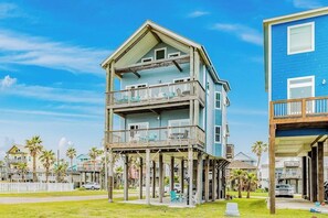 A two-story beachfront house with a balcony on the upper floor and a covered porch on the ground floor. - 8-Mile Beachfront - Gulf Views & Dog-Friendly (Galveston)