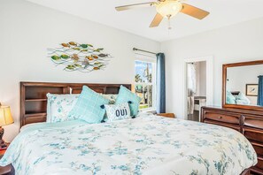 A bedroom with a bed, a ceiling fan, a wall art piece, a window with curtains, and a dresser. - 8-Mile Beachfront - Gulf Views & Dog-Friendly (Galveston)
