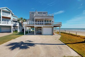 Ein Anwesen direkt am Strand mit einem zweistöckigen Haus, einer überdachten Veranda und einer Garage.