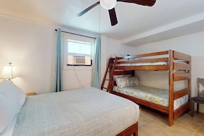 Quarto com cama de solteiro, beliche, ventoinha no teto, janela com cortinas e luminária.