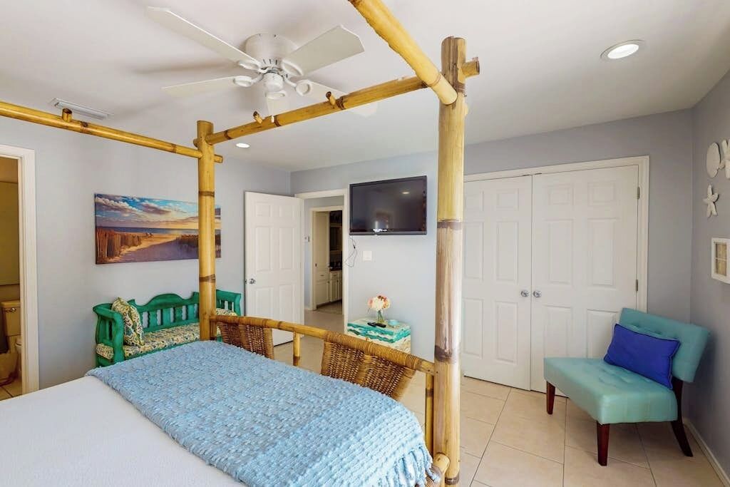 A room with a bed, a chair, a television, and a door.