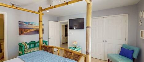 A room with a bed, a chair, a television, and a door.