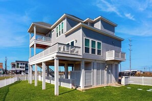 Une maison à deux étages située en bord de mer, dotée d’un balcon, d’une véranda et d’une cour clôturée.