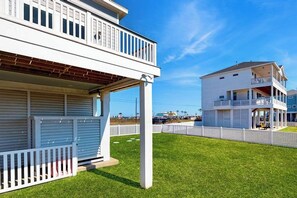 Ein zweistöckiges Wohnhaus mit überdachter Terrasse und einem umzäunten Hinterhof.
