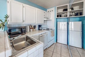 A kitchen with white cabinets, a microwave, stove, sink, and two refrigerators. - La Internacional Condominiums #202 (South Padre Island)