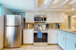 Una cocina moderna con electrodomésticos de acero inoxidable, armarios blancos y salpicadero de azulejos.