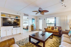 A living room with a television, a ceiling fan, a sofa, and a coffee table. - Saida Towers II #306 (South Padre Island)