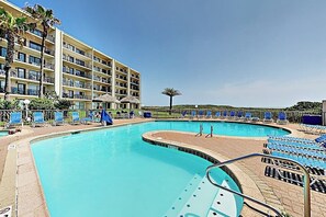 Ein Hotel mit großem Pool, mehreren Balkonen und Liegestühlen.