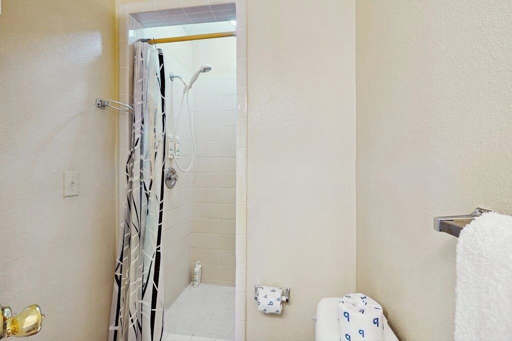 Un baño con ducha, inodoro y barra para toallas.
