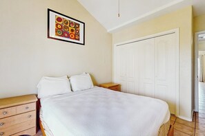 A bedroom with a bed, a nightstand, a dresser, a wardrobe, and a framed picture on the wall. - Dolphin Condominiums #20 (South Padre Island)