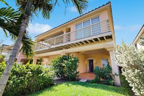 A two-story building with a balcony, a door, and a small garden area. - Hibiscus Hideaway Beach House (South Padre Island)
