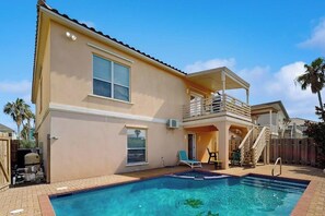 Une maison à deux étages avec une piscine, un patio couvert et une cour arrière clôturée.