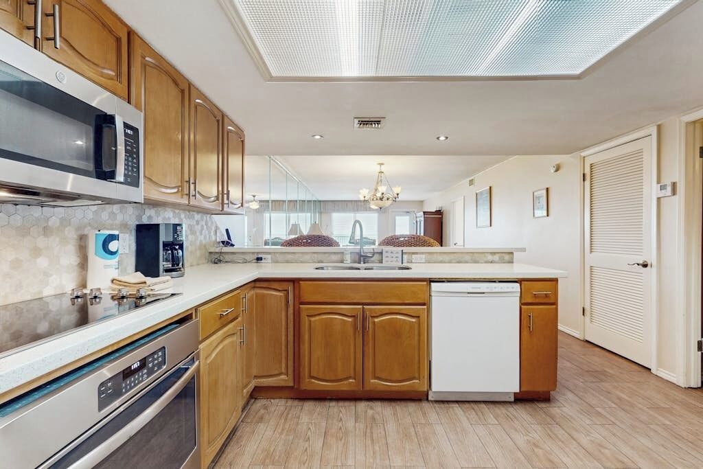 A modern kitchen with wooden cabinets, stainless steel appliances, and a skylight.