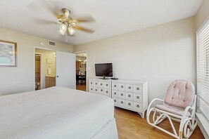 Una camera da letto con un letto, una televisione su un comò, una poltrona a dondolo e una ventola a soffitto.