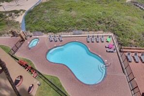 An aerial view of a hotel with a large swimming pool, sun loungers, and a surrounding deck area. - Suntide II Condominiums #306 (South Padre Island)