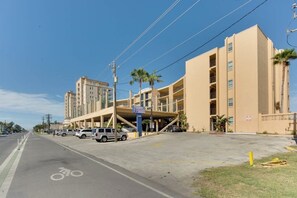 Ein mehrstöckiges Gebäude mit überdachtem Parkbereich, einer Fahrradspur und blauem Himmel.