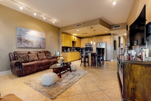 A spacious living room with a brown leather sofa, a coffee table, and a rug. - Sapphire Condominiums #603 (South Padre Island)