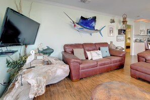 Ein Wohnzimmer mit einer Ledersofa, einem aufgehängten Fisch und einem Fernseher.