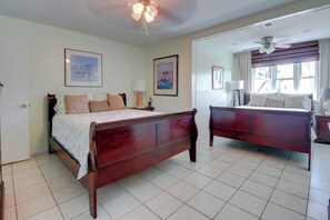 A bedroom with a wooden bed, a bedside table, a lamp, and a ceiling fan. - Mezquite House - Ocean Views, Sleeps 16, Dogs OK (South Padre Island)