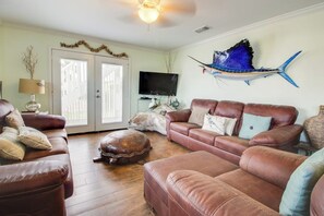 Ein Wohnzimmer mit Ledersofas, einem Fernseher und einem dekorativen Fisch an der Wand.