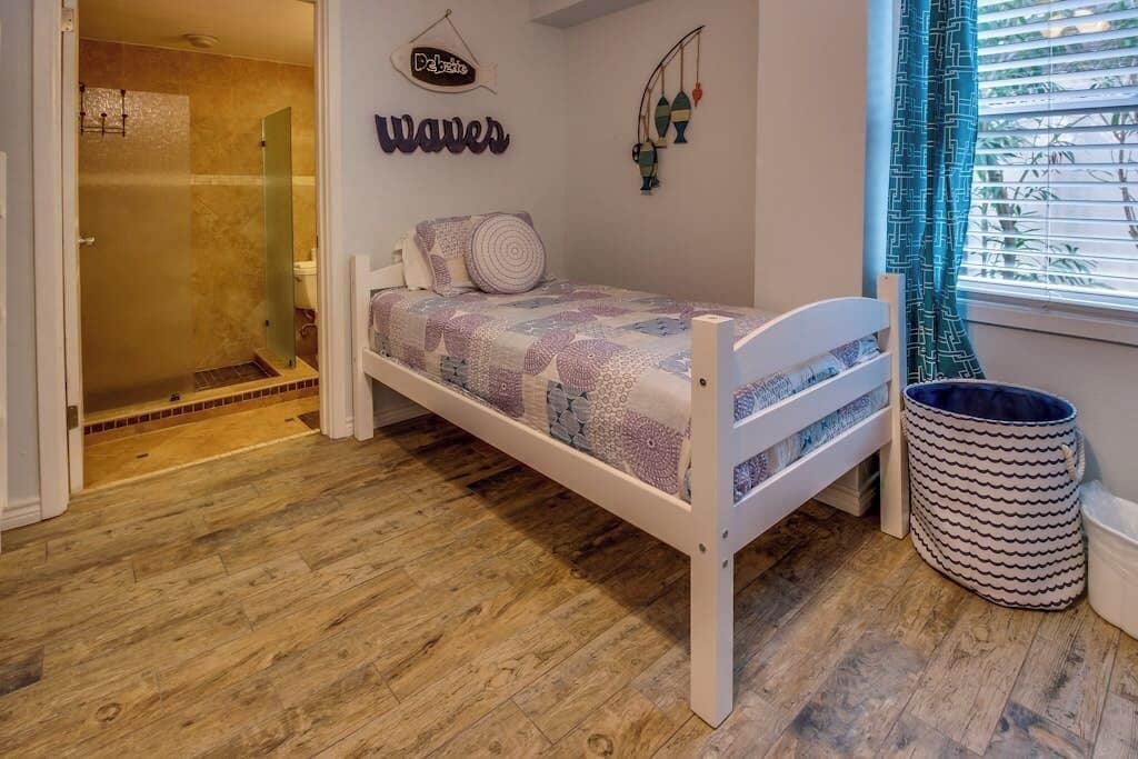 Een slaapkamer met een bed, een hanglamp, een bord aan de muur en een raam met gordijnen.