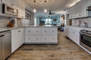 A kitchen with white cabinetry, a central island with drawers, a stainless steel oven, and pendant lighting. - Mezquite House - Ocean Views, Sleeps 16, Dogs OK (South Padre Island)