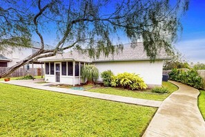 A residential house with a front porch, a lawn, and a curved driveway. - Birder's Heaven at 621 Palm (Laguna Vista)