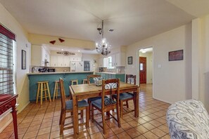 A spacious kitchen with a dining area, wooden chairs, and a chandelier. - Birder's Heaven at 621 Palm (Laguna Vista)