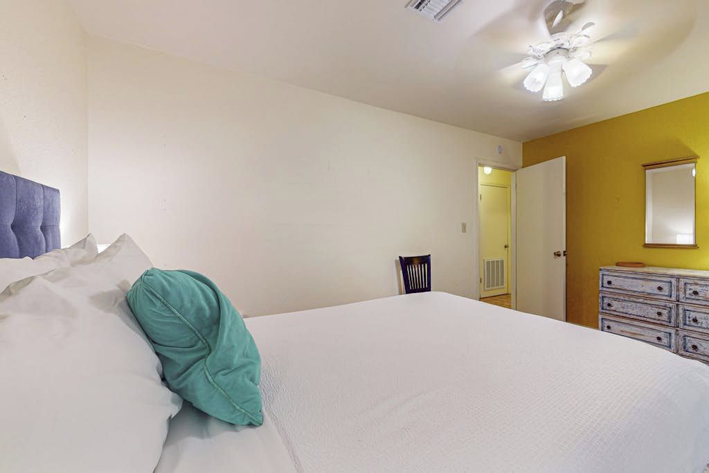 Ein Schlafzimmer mit Bett, Kommode und einer Tür zu einem anderen Raum.