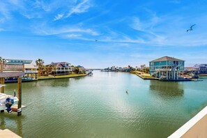 A waterfront property with a dock, a boat, and a building with a balcony. - Mon Repose - Bayfront Home with Big Deck (Jamaica Beach)