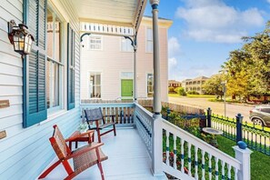 A porch with two rocking chairs, a small table, and a green door. - Blue Sky Getaway - Private Pool & Historic Charm (Galveston)