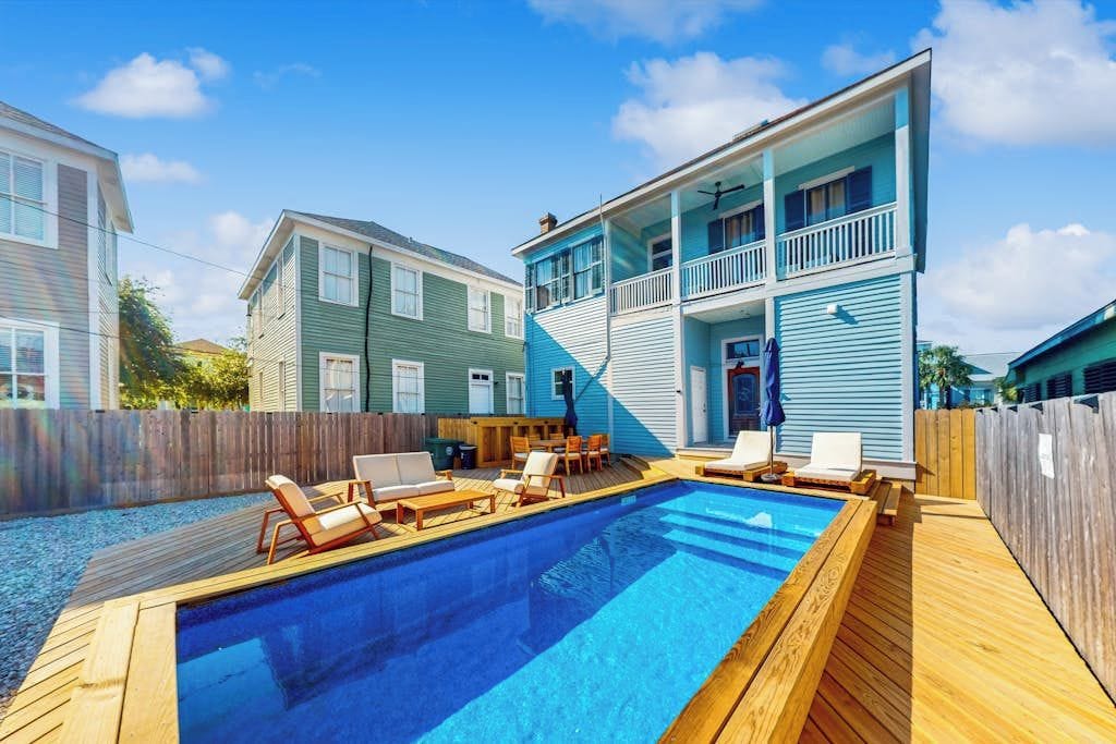 Une propriété résidentielle dotée d’une piscine, d’une terrasse en bois et d’une maison à deux étages avec un balcon.