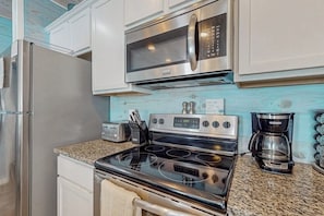 A kitchen with a stainless steel refrigerator, a microwave, an oven, a toaster, and a coffee maker. - The Coral Cove - Walk to Beach, Pool & Dogs OK (Port Aransas)