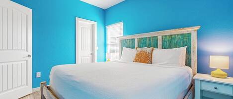 A bedroom with a bed, a nightstand, a ceiling fan, and a door.