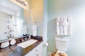 Ein Badezimmer mit einem Marmorwaschbecken, einer Toilette und einem Spiegel mit einem Handtuch an der Wand.
