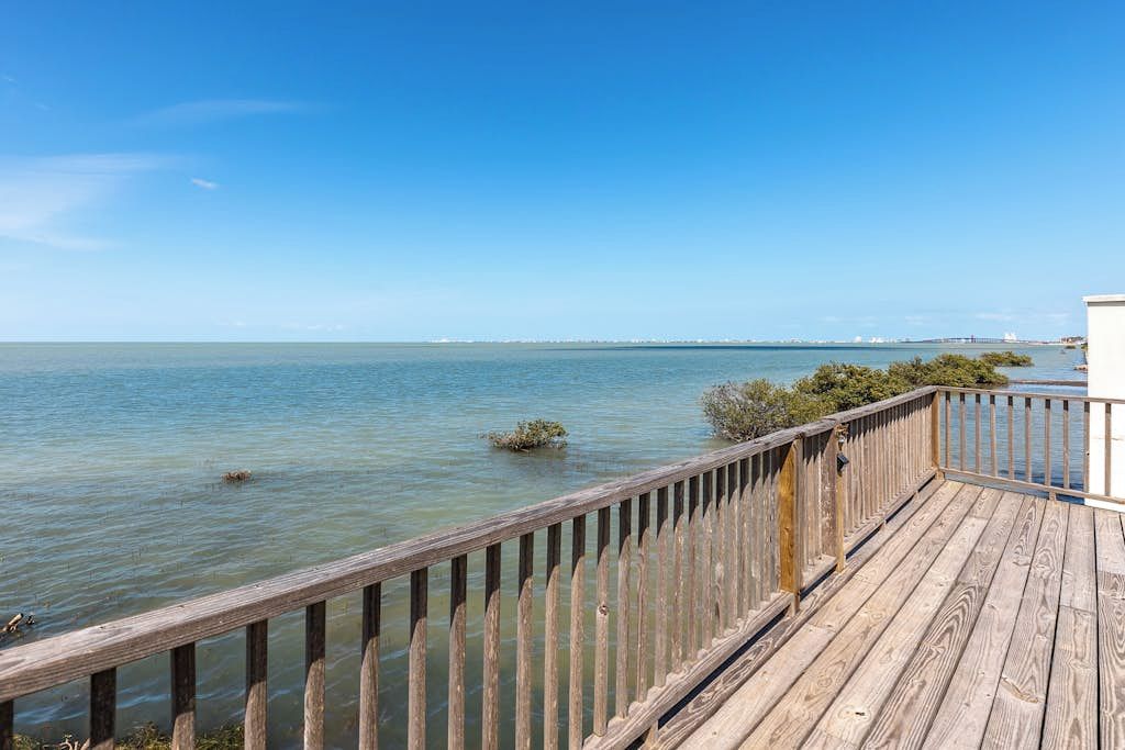 Eine Holzterrasse mit Blick auf ruhiges Wasser und einen klaren Himmel.