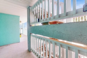 Een balkon met een witte reling, een turquoise muur en een uitzicht op de lucht.