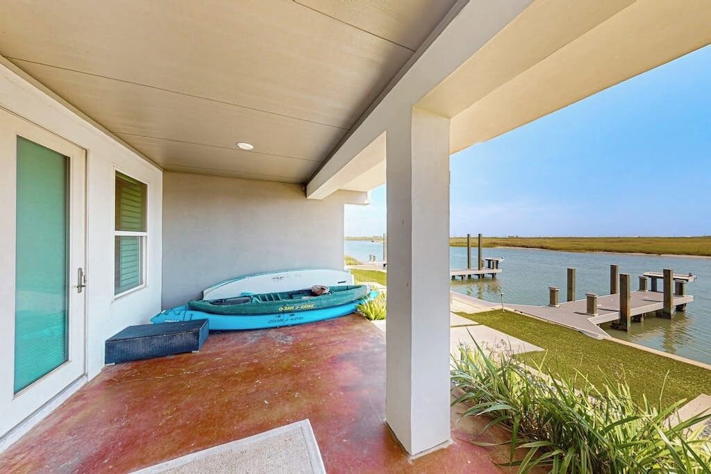 A covered outdoor area with a boat dock, a door, and a view of a body of water.