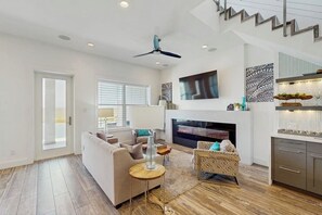 A spacious living area with a sofa, a coffee table, and a fireplace. - Padre Villa 102 - Waterfront Dock, Walk to Beach (Corpus Christi)