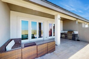 Ein überdachter Patio-Bereich mit Sitzgelegenheit und Grillstation.