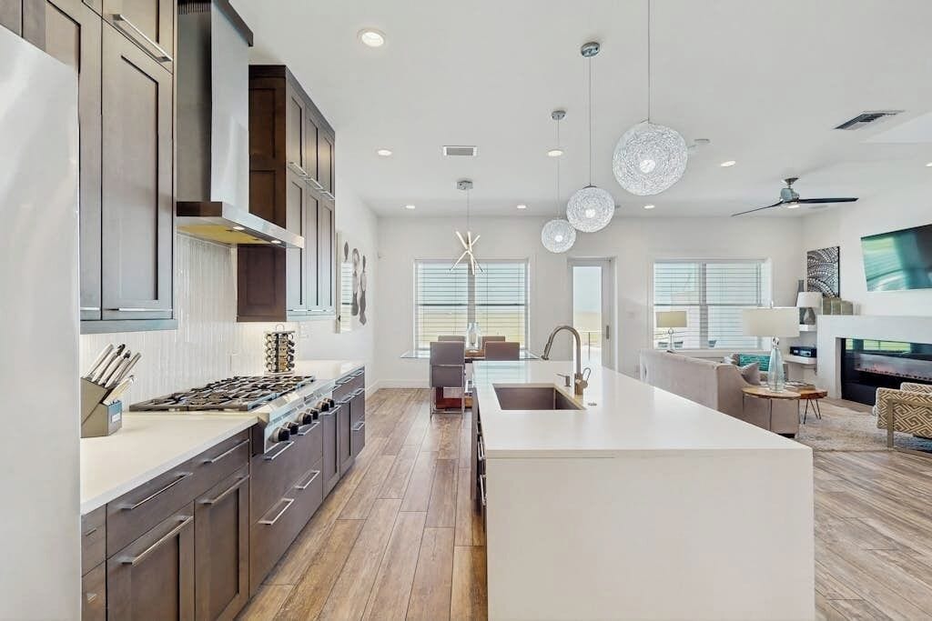 A modern kitchen with a central island, built-in appliances, and pendant lighting.