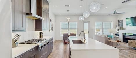 A modern kitchen with a central island, built-in appliances, and pendant lighting.