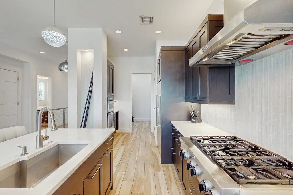 Une cuisine moderne dotée d’une cuisinière en acier inoxydable, d’un évier à deux bacs et de meubles de rangement en bois.